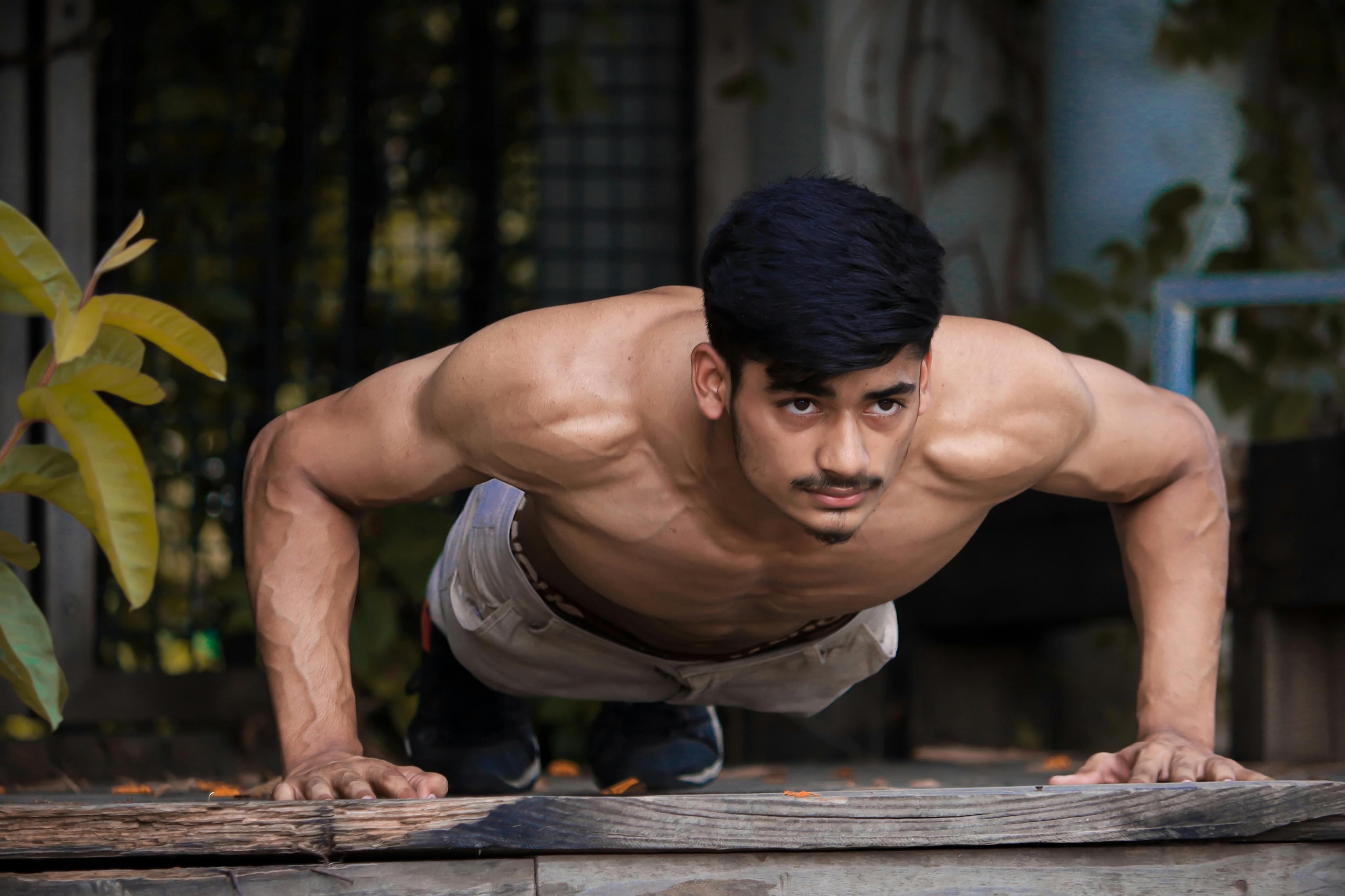 Muscular South Asian man doing push-ups outdoors, showcasing strength and fitness.